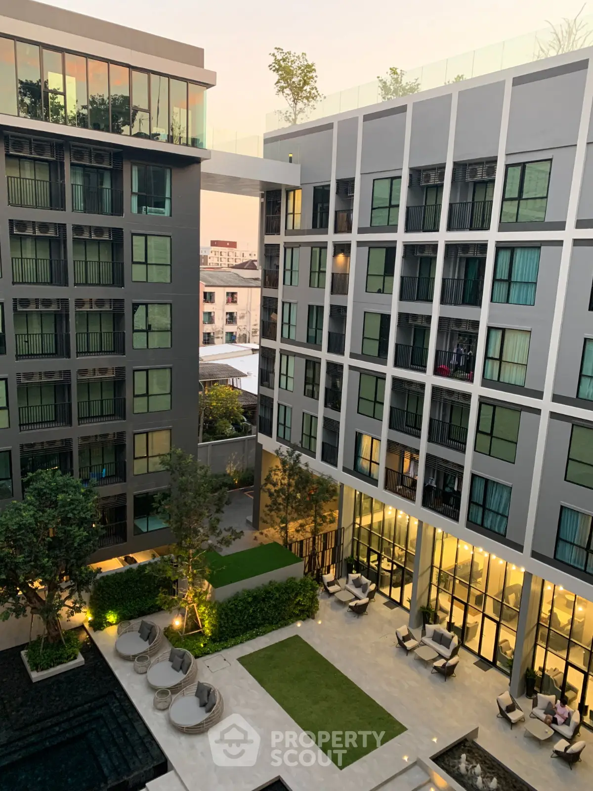 Modern apartment building with stylish courtyard and outdoor seating area, perfect for urban living.