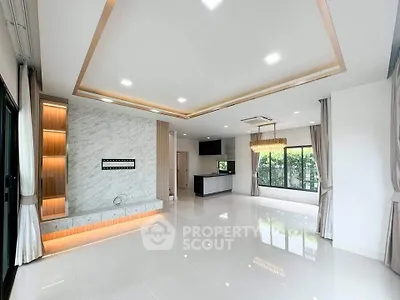 Spacious modern living room with elegant lighting and open kitchen layout, featuring large windows and marble accents.