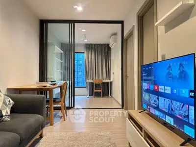 Modern living room with sleek furniture and large TV, adjacent to a study area with glass partition.