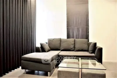 Modern living room with sleek black sofa and glass coffee table, perfect for stylish urban living.