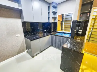 Modern kitchen with sleek black marble countertops and ample storage space.