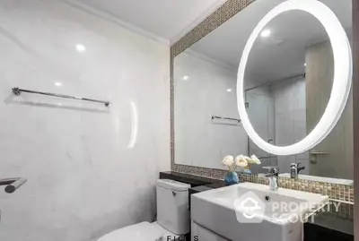 Modern bathroom with stylish circular LED mirror, elegant tiling, and sleek fixtures, perfect for contemporary living.