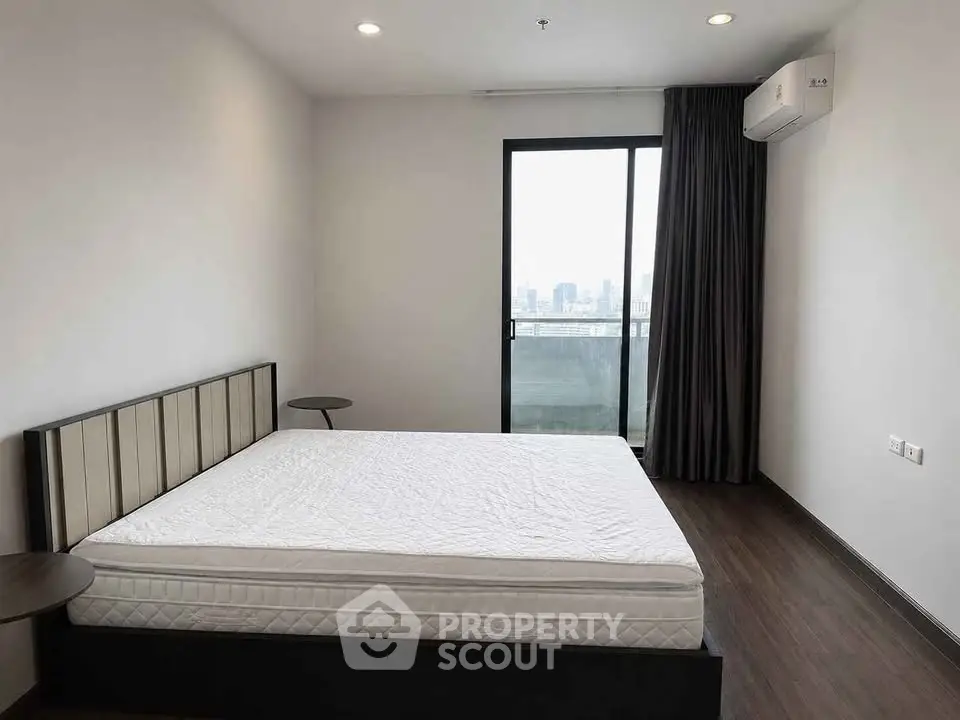 Spacious bedroom with modern design and city view balcony access.