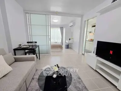 Modern open-plan living room with cozy seating and TV, adjacent to a stylish bedroom.
