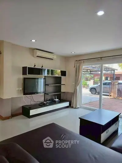 Modern living room with sleek entertainment unit and large sliding glass doors leading to outdoor area.