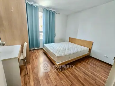 Spacious bedroom with wooden flooring and natural light