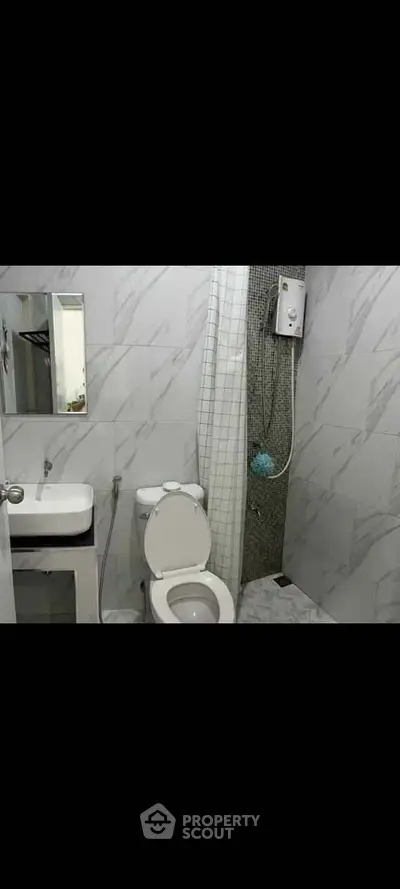 Modern bathroom with sleek white fixtures and marble tile design.