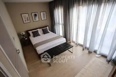 Spacious bedroom with modern decor and large windows for natural light.