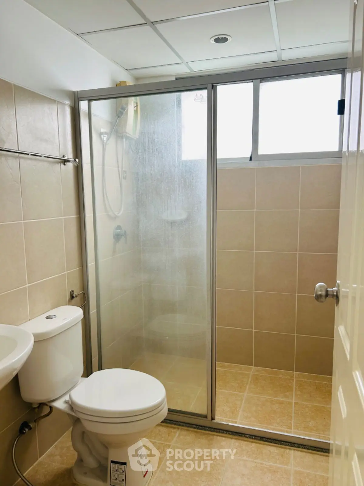 Modern bathroom with glass shower enclosure and tiled walls.
