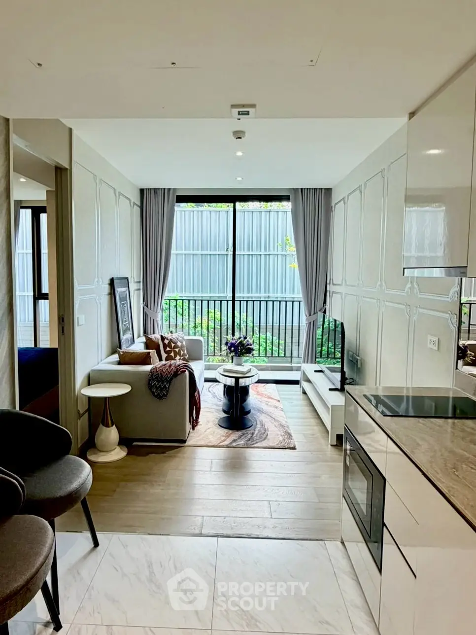 Modern open-plan living room with kitchen, featuring stylish decor and large window view.