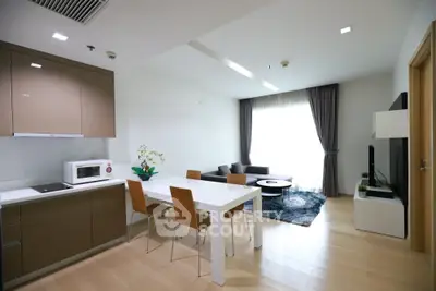 Modern open-layout kitchen and living room with sleek furniture and natural light.