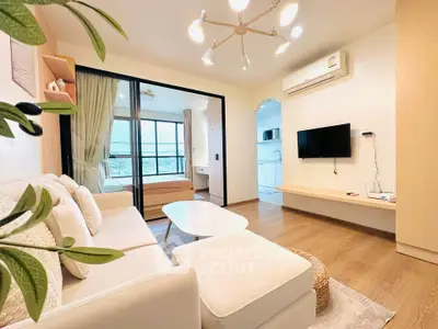 Modern living room with cozy sofa, stylish lighting, and open view to bedroom and kitchen.