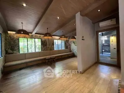 Spacious living room with wooden flooring and natural light, perfect for relaxation and gatherings.