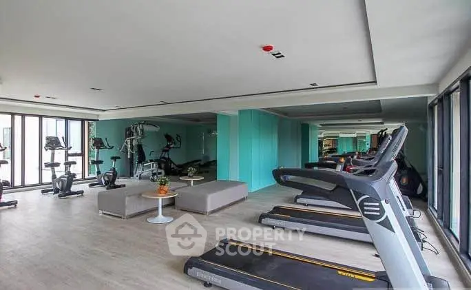 Spacious modern gym with state-of-the-art equipment and large windows for natural light.