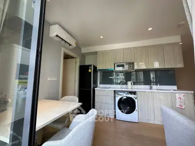 Modern kitchen with dining area, featuring washing machine and sleek appliances in a stylish apartment.