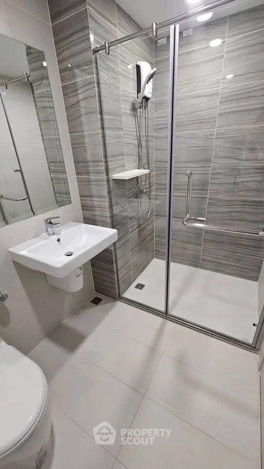 Modern bathroom with sleek shower enclosure and stylish sink in contemporary apartment.