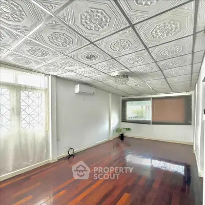Spacious living room with ornate ceiling and hardwood floors, perfect for elegant gatherings.