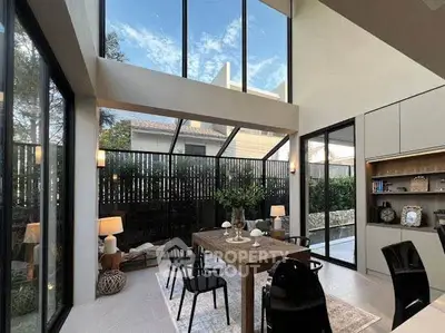 Stunning modern dining area with high ceilings and large windows offering natural light and garden views.