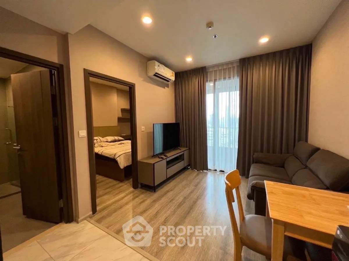 Modern living room with cozy furniture and natural light, adjacent to a stylish bedroom.