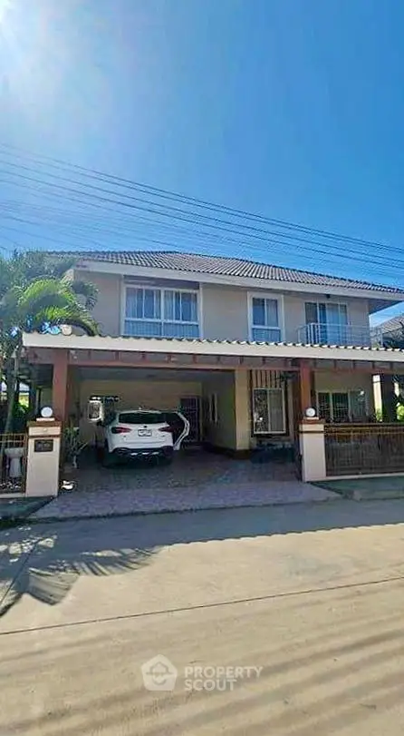 Charming two-story house with carport and lush greenery in a serene neighborhood.