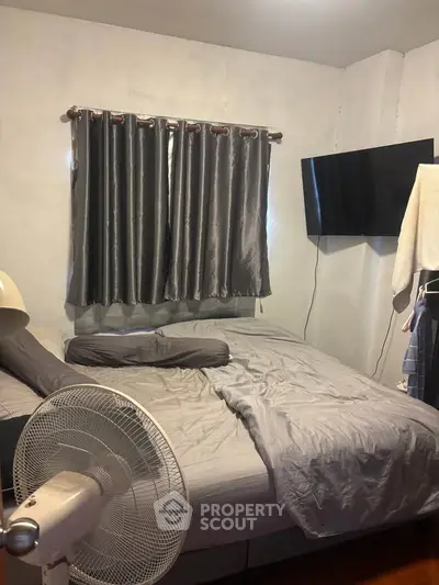 Cozy bedroom with modern decor, featuring a wall-mounted TV and stylish gray curtains.