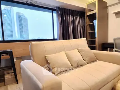 Modern living room with city view, featuring a cozy beige sofa and elegant decor.