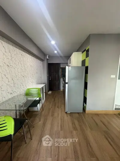 Modern kitchen with sleek design, featuring a stainless steel fridge and stylish green chairs.