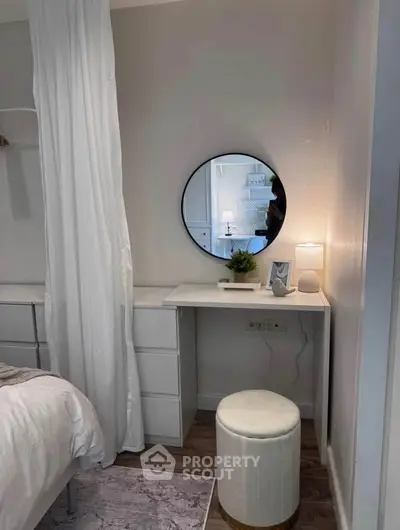 Cozy bedroom corner with modern vanity, round mirror, and soft lighting.