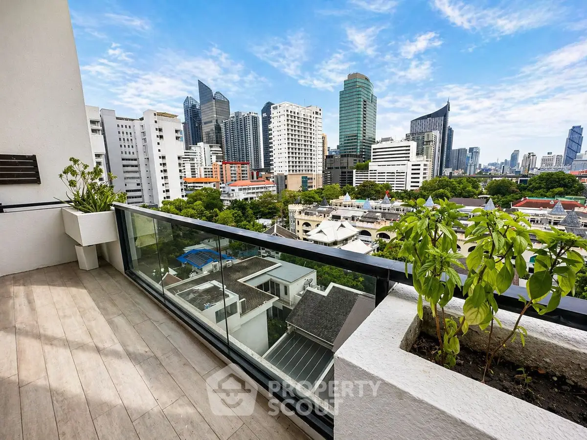 Stunning cityscape view from a modern balcony with glass railing and lush greenery.