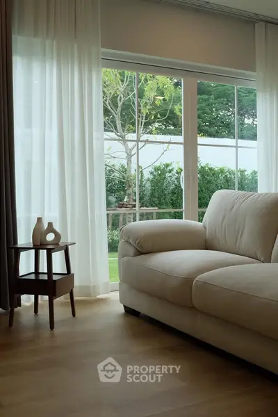 Elegant living room with plush sofa and garden view through large windows