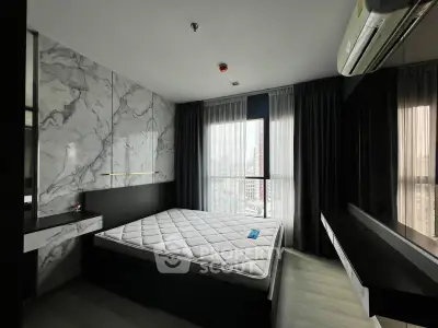Modern bedroom with marble accent wall and large window offering city views.