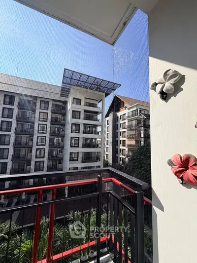 Modern apartment balcony with scenic view of urban architecture and lush greenery.