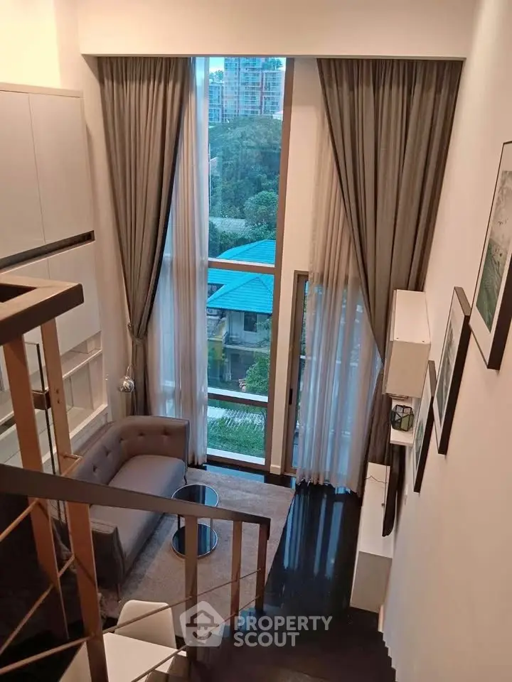 Modern loft-style living room with high ceilings and large windows offering a stunning view.