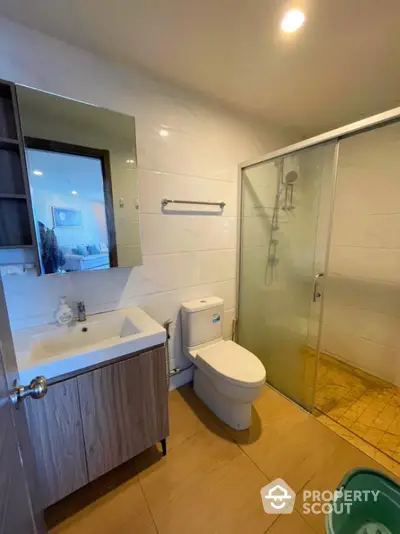 Modern bathroom with glass shower and sleek vanity in contemporary apartment.