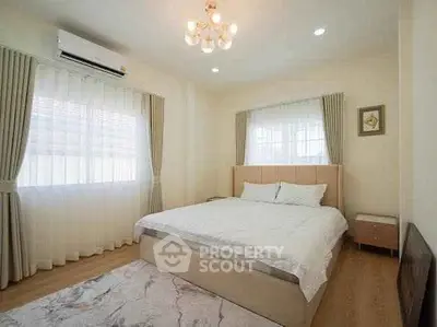 Spacious bedroom with elegant decor and natural light, featuring a comfortable bed and stylish curtains.