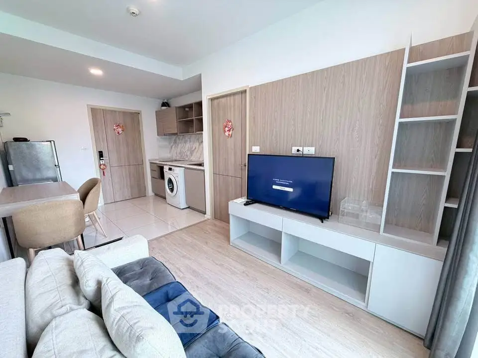 Modern living room with open kitchen, featuring sleek furniture and integrated appliances.