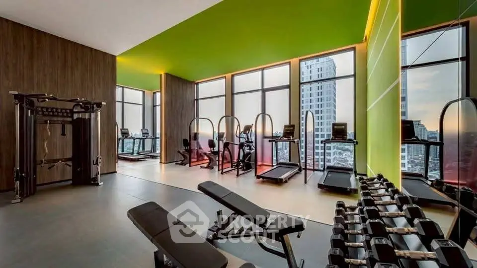 Modern gym with city view, featuring treadmills and weights in a high-rise building.