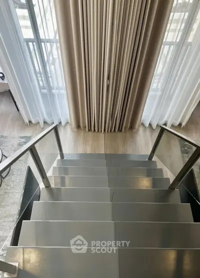Elegant staircase with modern design and floor-to-ceiling curtains in a luxury home