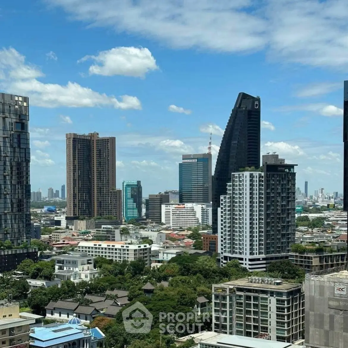 Stunning cityscape view showcasing modern skyscrapers and lush greenery under a clear blue sky.