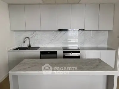 Modern kitchen with sleek white cabinetry and marble countertops, featuring built-in appliances and a stylish island.
