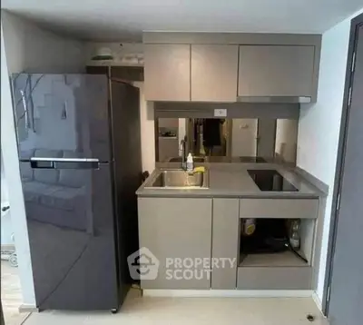Modern compact kitchen with sleek cabinetry and stainless steel appliances in a stylish apartment.