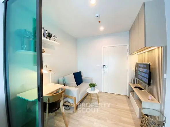 Modern living room with stylish decor and natural light, featuring a cozy sofa and wall-mounted TV.