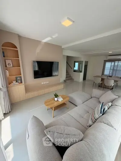 Spacious modern living room with cozy sofa and wall-mounted TV, perfect for relaxation.