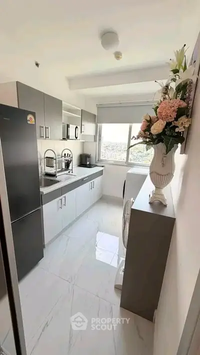 Modern kitchen with sleek cabinets and large window offering city views