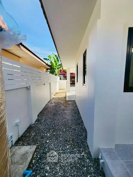 Charming side pathway of a modern home with clean lines and gravel path.