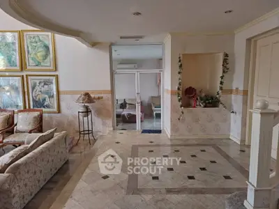Elegant living room with stylish decor and marble flooring, featuring a cozy seating area and artistic wall paintings.