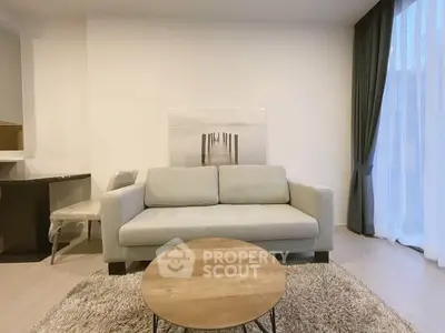 Modern living room with cozy sofa, stylish decor, and natural light from large windows.