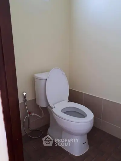 Simple bathroom with standard toilet and tiled floor, ideal for minimalist design enthusiasts.