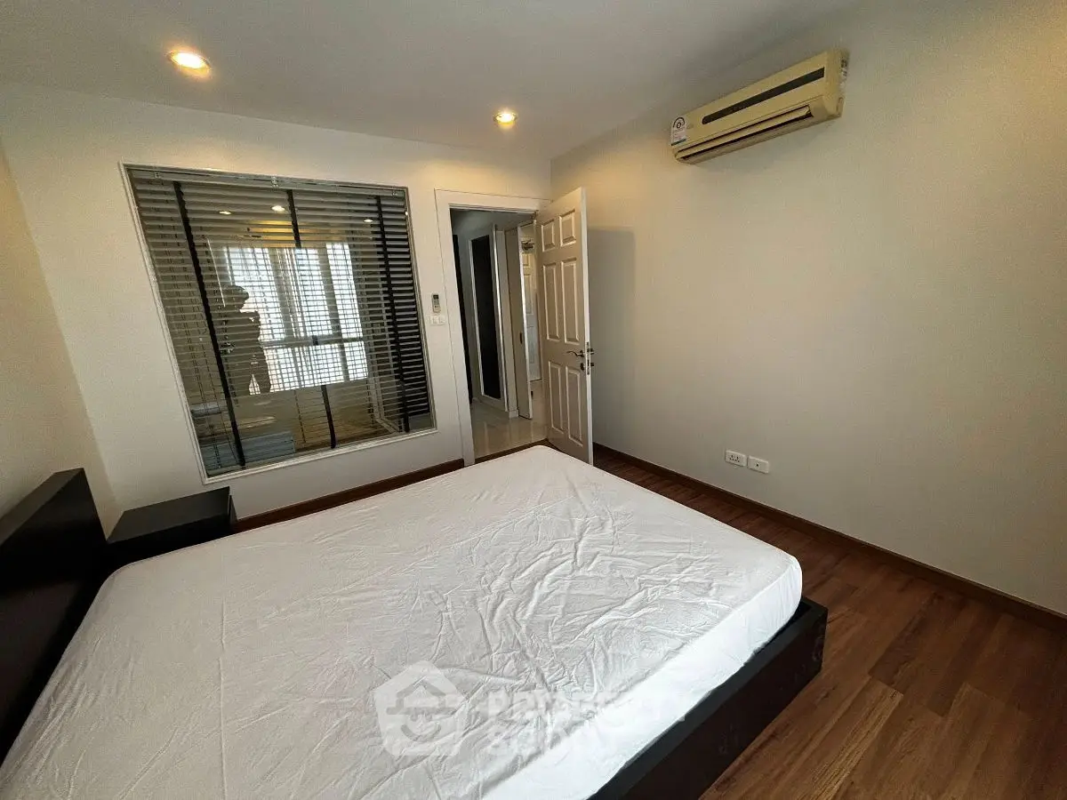 Modern bedroom with wooden flooring and air conditioning unit