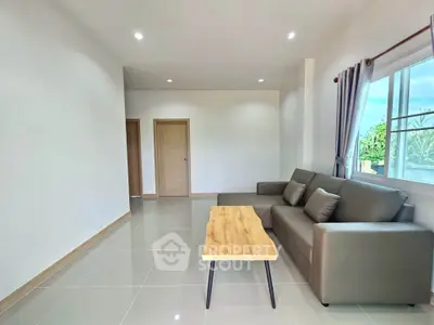 Spacious living room with modern sofa and natural light, perfect for relaxation.